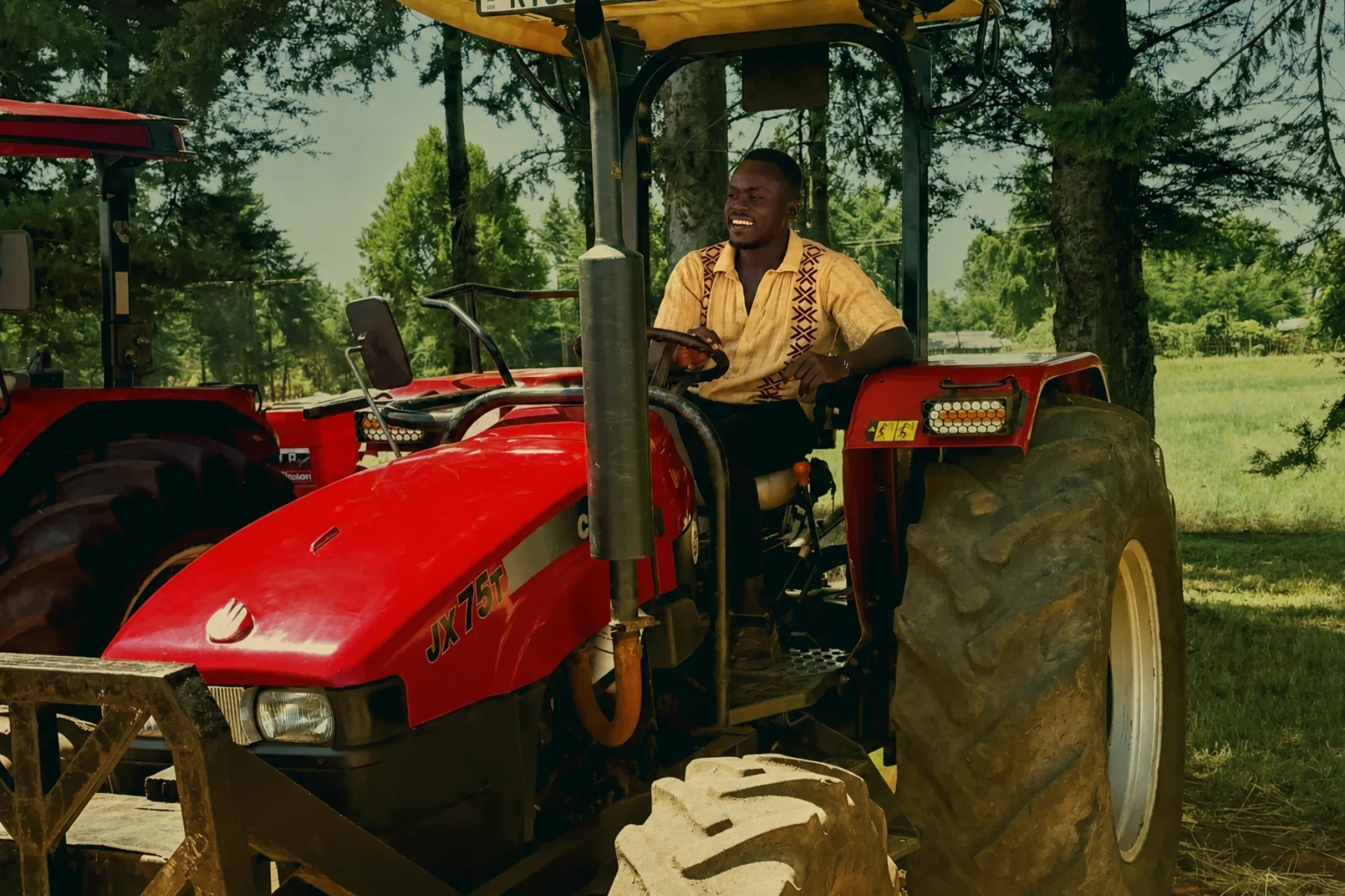 Wycliffe smiling while driving a red tractor on a farm